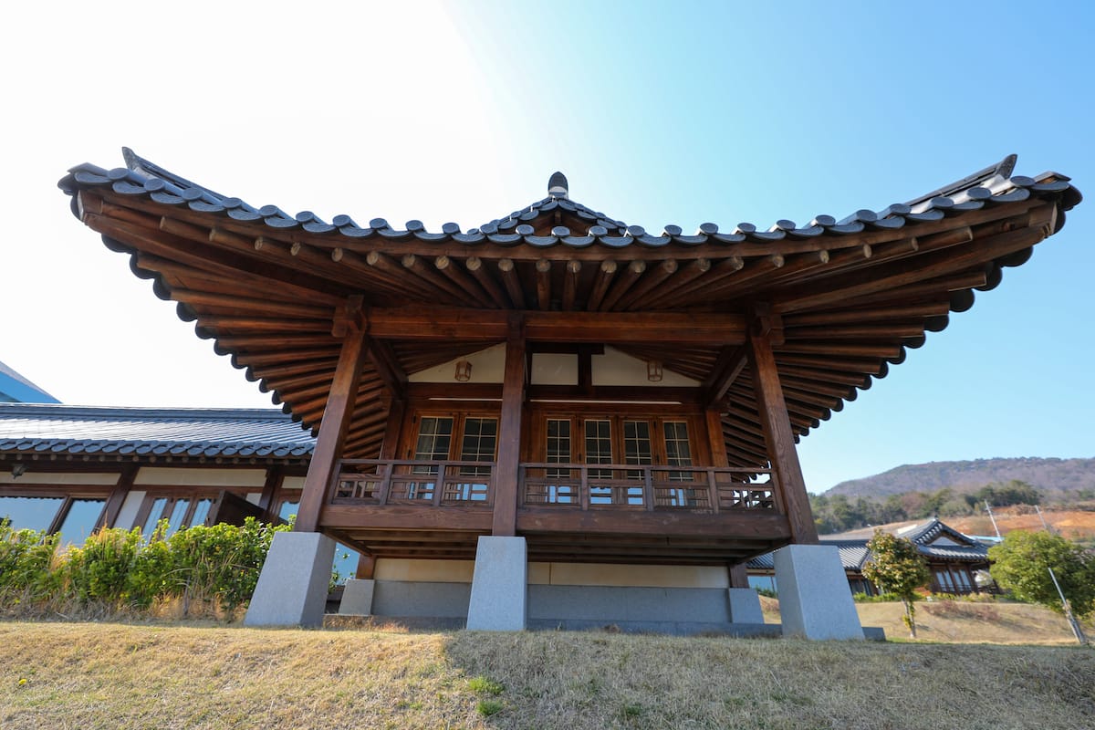 A traditional wooden building with a tiled roof, large windows, and a balcony.