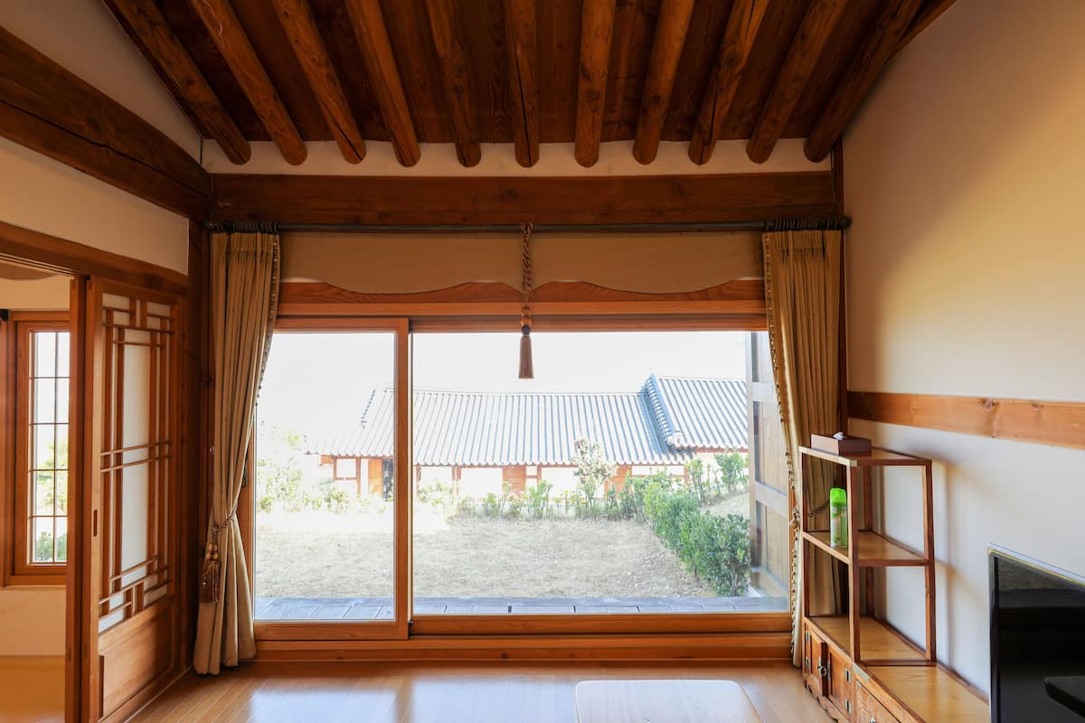 A room with a wooden ceiling, sliding glass doors, a TV, and a wooden shelf.