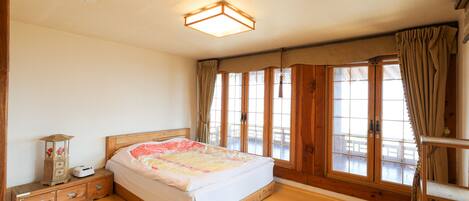 A bedroom with a wooden bed, a nightstand, a lamp, and a window with curtains.