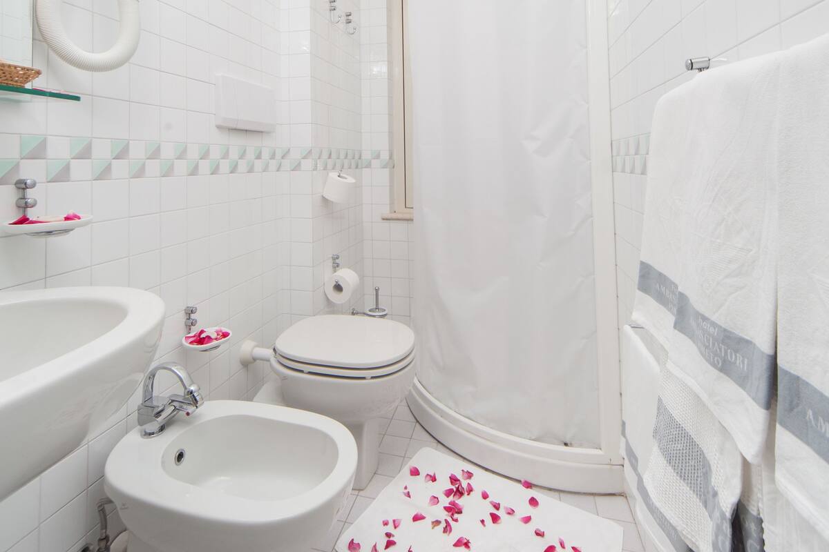 A bathroom with a bathtub, a bidet, a toilet, and a shower curtain.