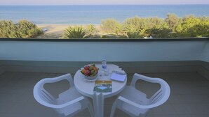 A balcony with a table set for two, a bowl of fruit, a water bottle, and a menu. - Hotel Ambasciatori (Pineto)