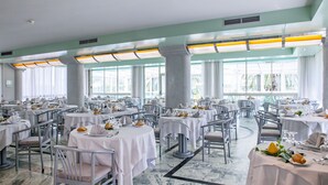 A spacious dining area with multiple tables set for a formal meal, large windows, and a clean, modern interior. - Hotel Ambasciatori (Pineto)