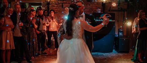 A wedding reception in a rustic wooden hall with a dance floor and a mounted deer head on the wall.