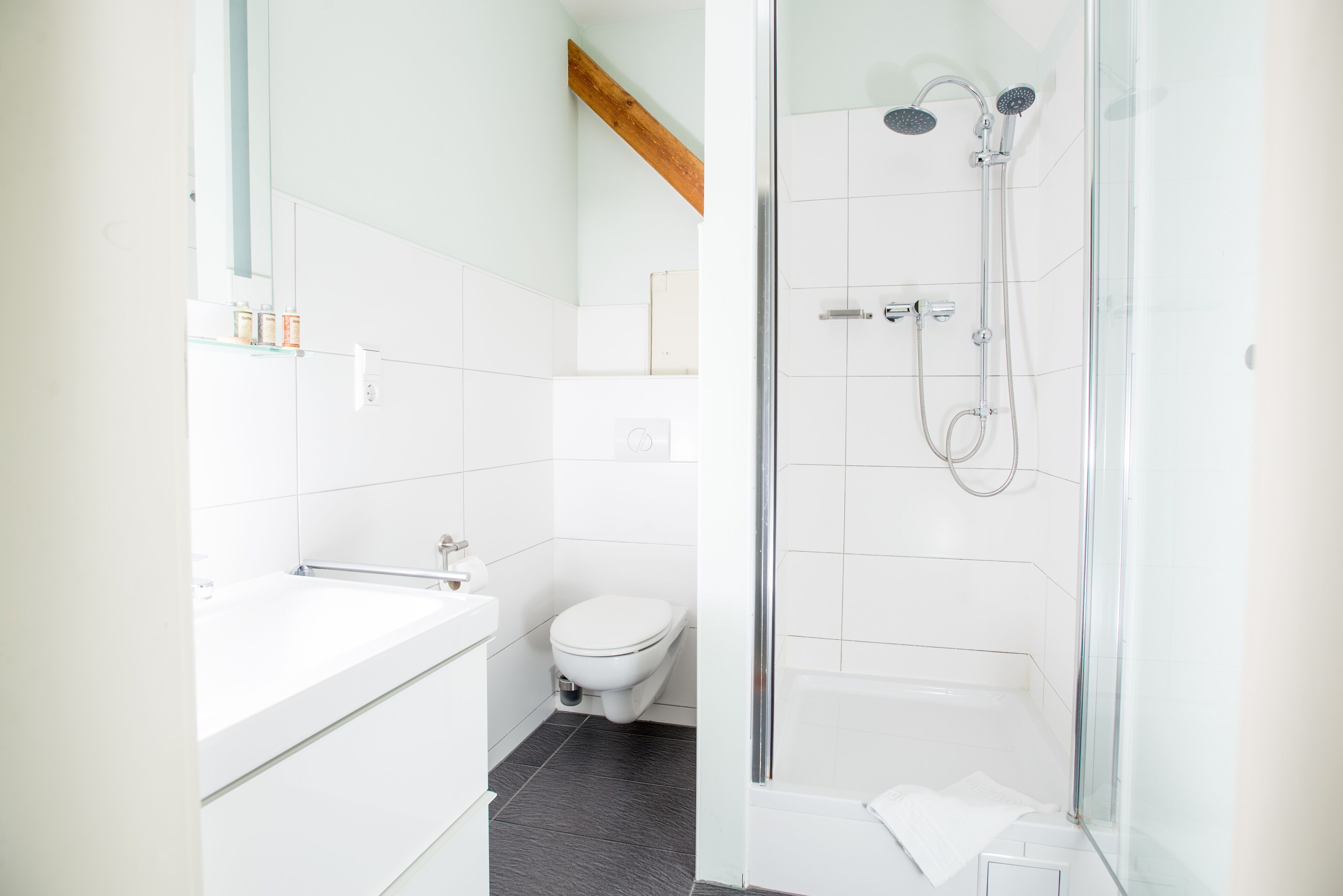 A modern bathroom with a bathtub, toilet, and glass-enclosed shower area.