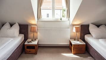 Una camera da letto con due letti, una finestra con tende, un termosifone e lampade sui comodini.