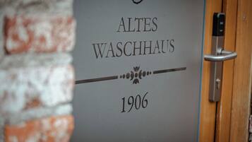 Une porte portant l’inscription « ALTES WASCHHAUS 1906 » et dotée d’une poignée de porte moderne.