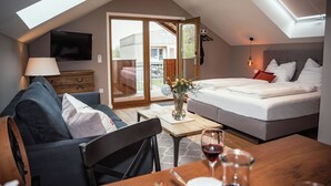 A modern bedroom with a skylight, a sofa, a bedside table with a vase, and a bed with pillows.