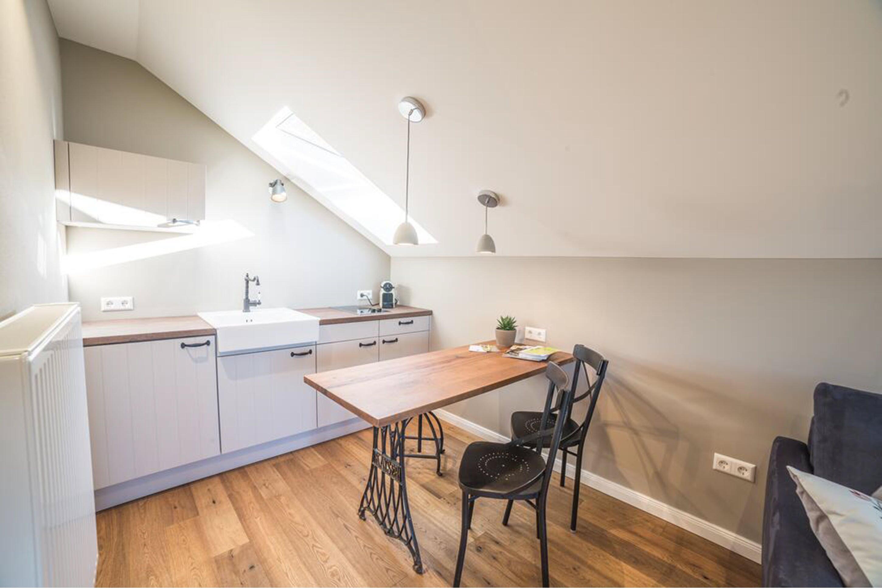 Cocina compacta con una mesa de madera, dos sillas, un lavamanos y una ventana sobre la encimera.