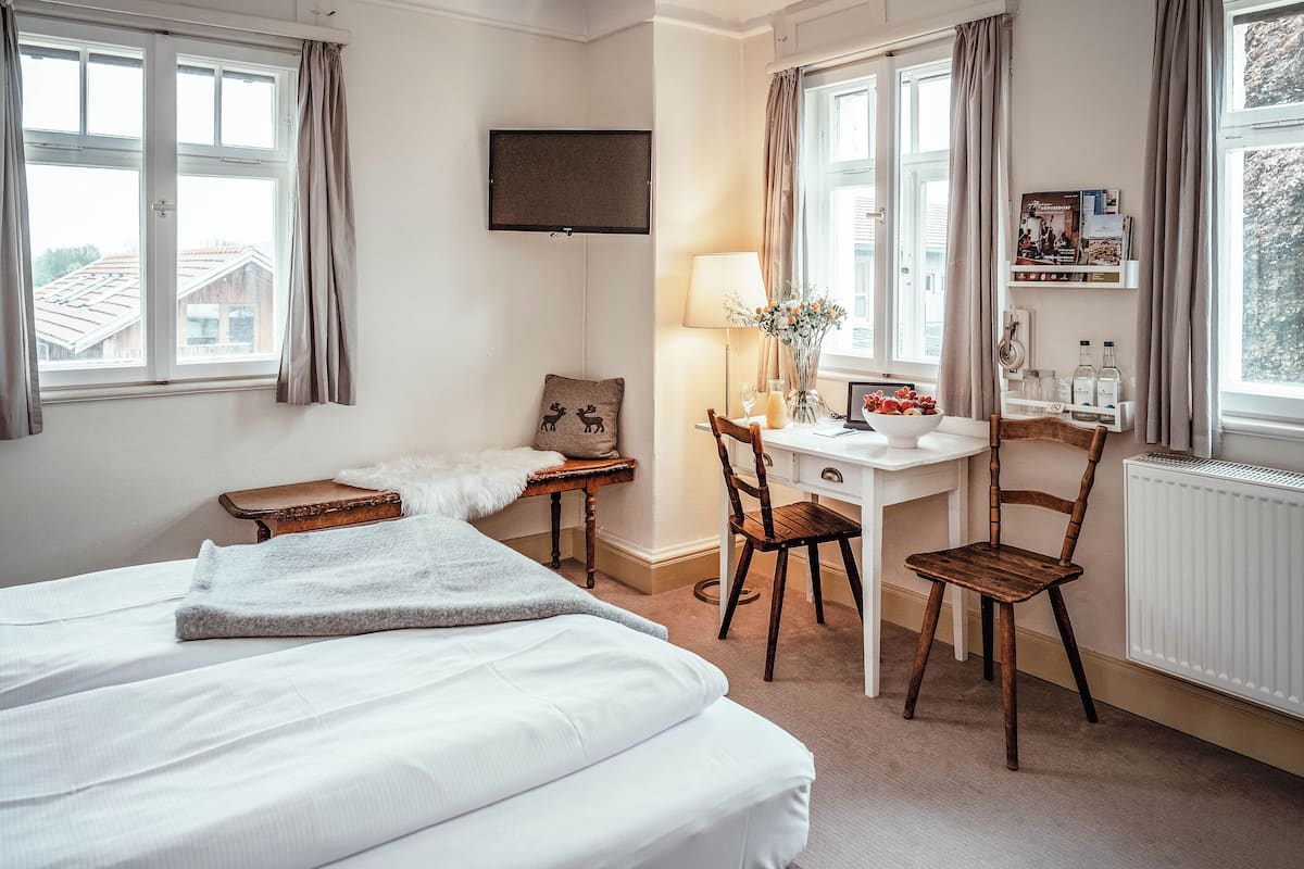 Une chambre d’hôtel avec un lit, un bureau et une chaise, une lampe et un téléviseur fixé au mur.