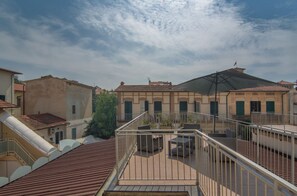 A rooftop terrace with a pergola, outdoor seating, and a view of adjacent buildings. - Hotel Arcangelo (Viareggio)
