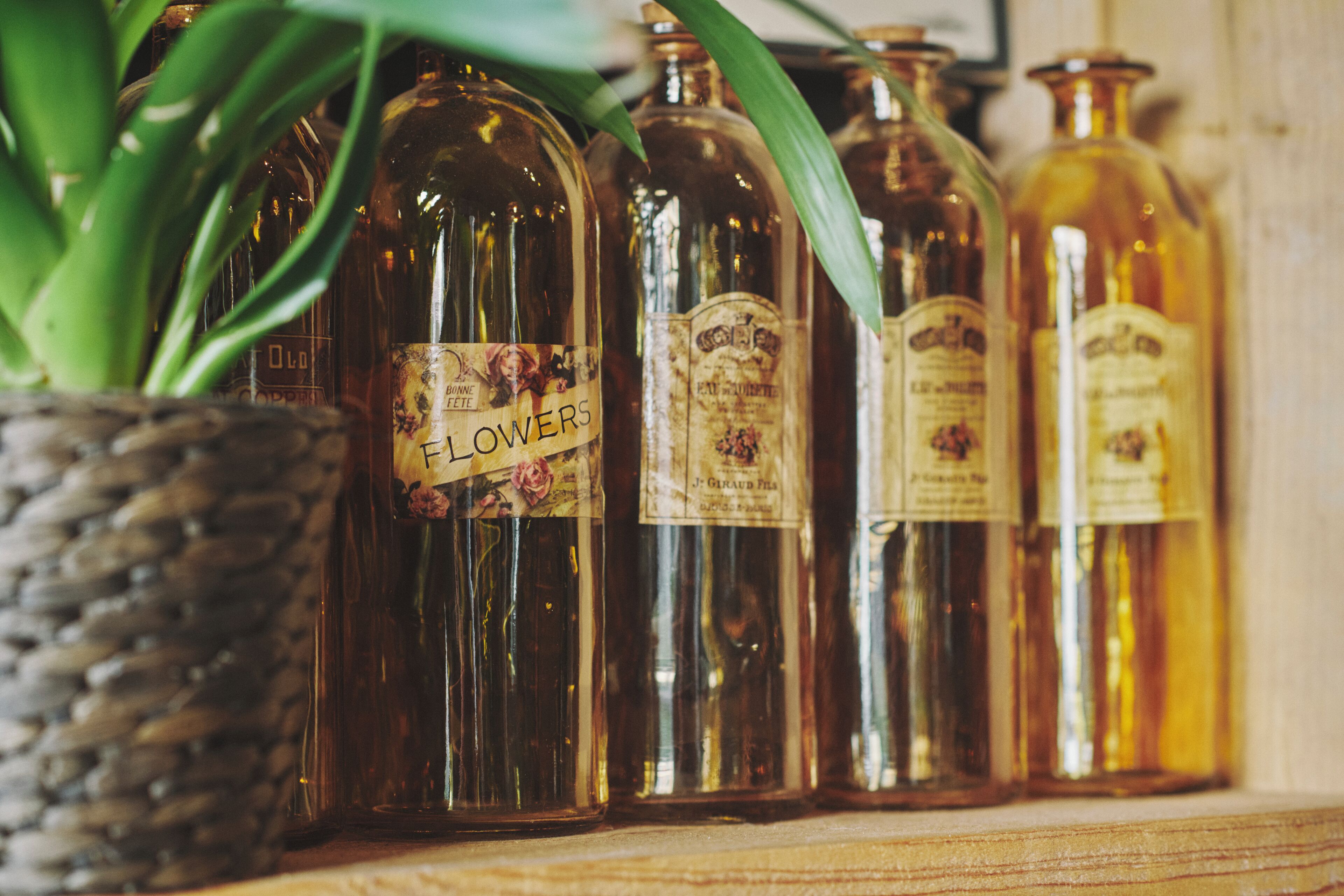 Een rij vintage parfumflesjes met etiketten, geplaatst op een plank.