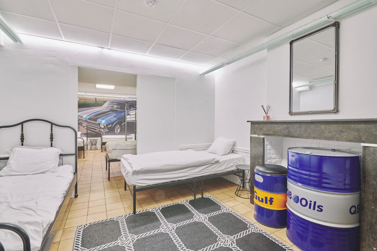 Een kamer met twee bedden, een tafeltje, een spiegel en twee vaten met de tekst 'Gulf Oils'.