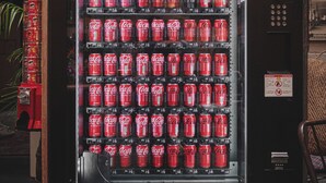 Máquina de vendas com várias fileiras de latas de Coca-Cola.