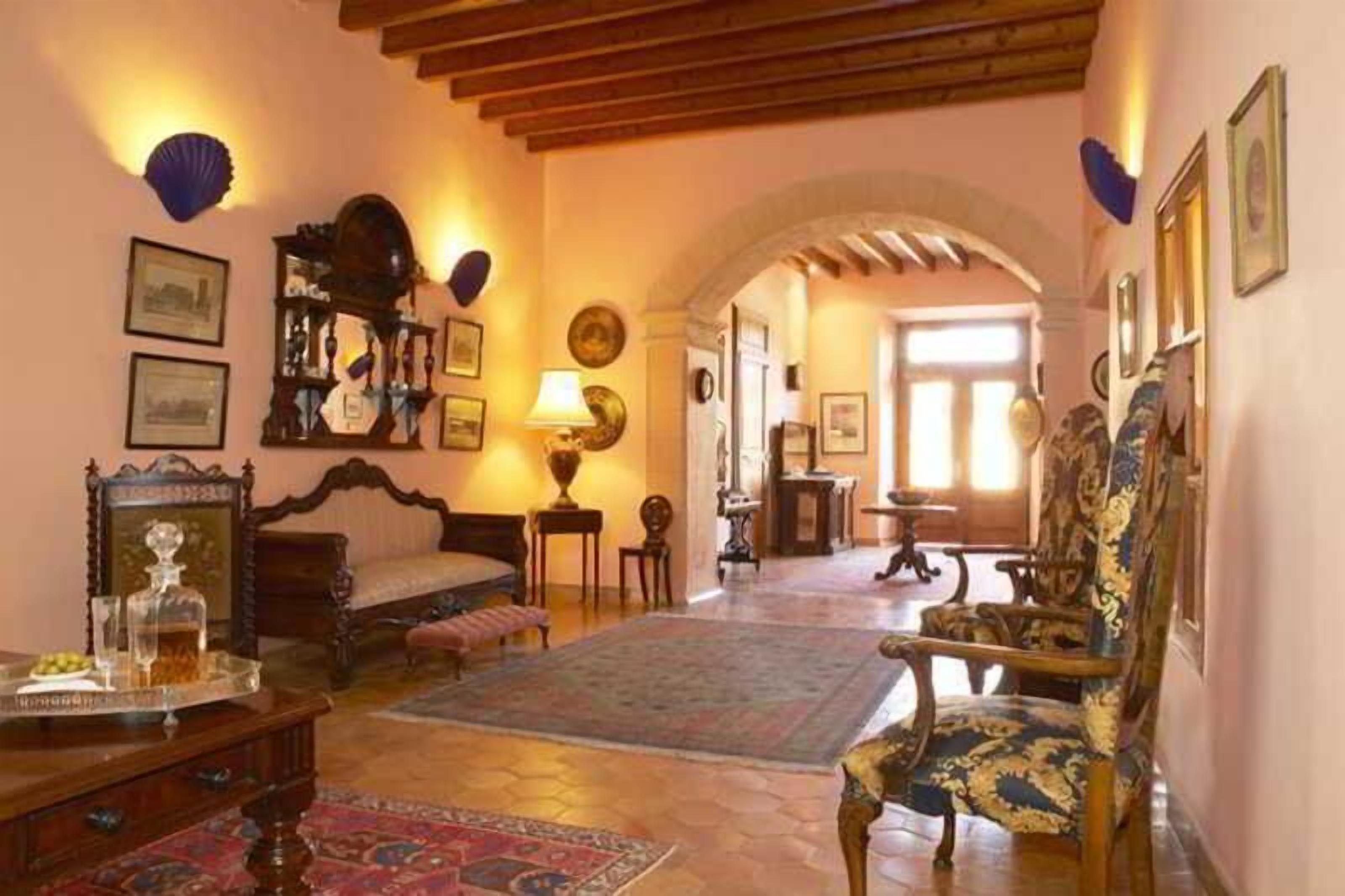 A traditional room with a wooden ceiling, a bed, a chair, a table, and a rug.