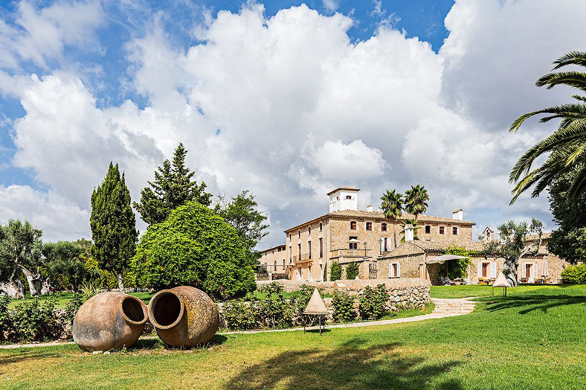 A historic building with a stone facade, surrounded by lush greenery and large pottery sculptures.