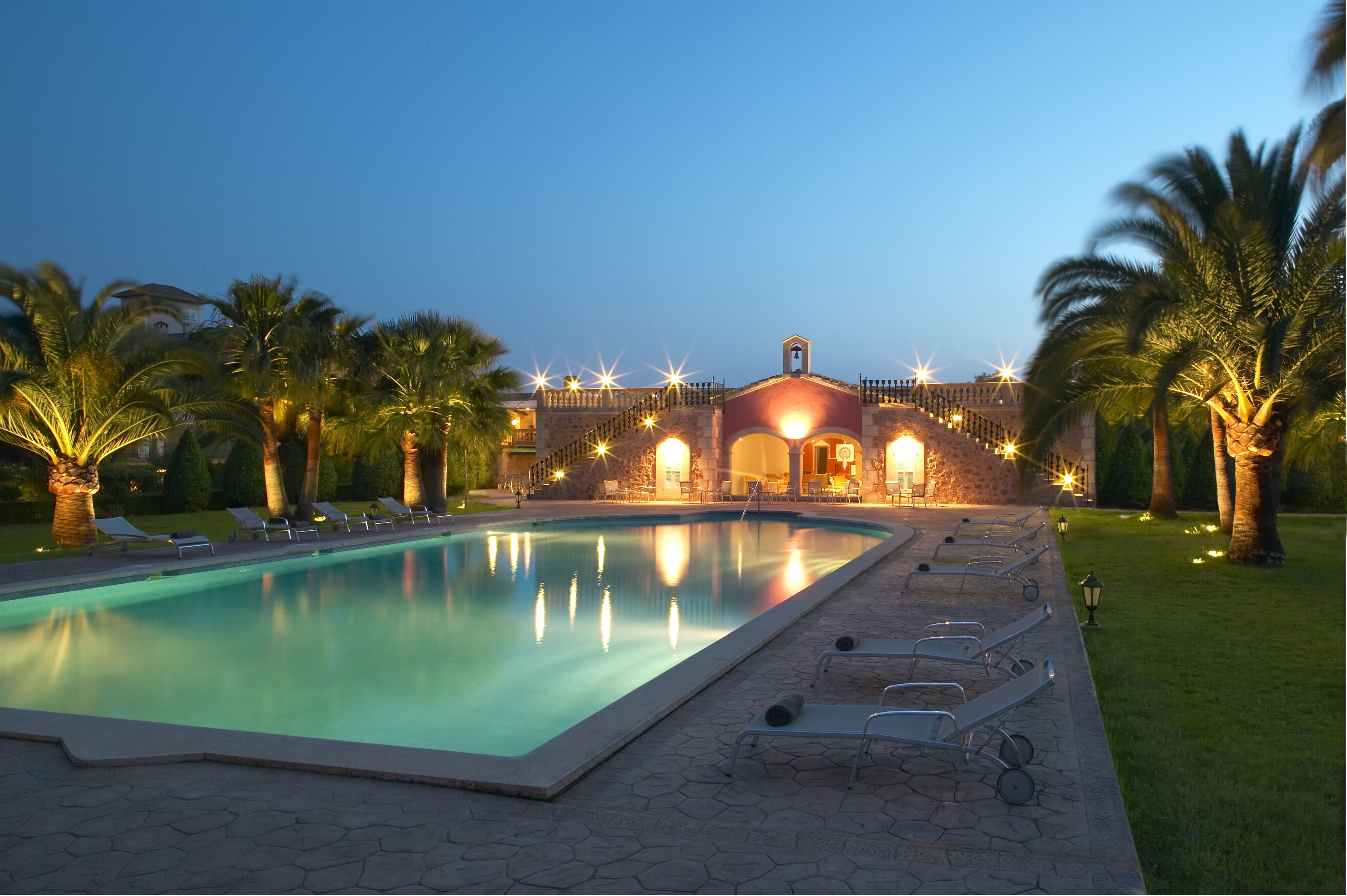 A swimming pool with lounge chairs and a building with a bell tower in the background.