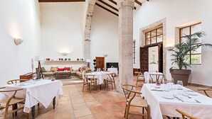 A spacious dining area with high ceilings and stone pillars, featuring multiple tables set for dining. - Reads Balance Hotel (Santa Maria del Camí)