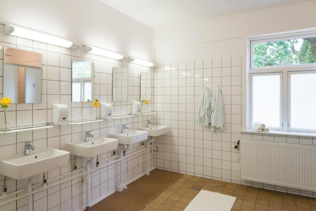 A modern bathroom with three sinks, a large mirror, and a window providing natural light.