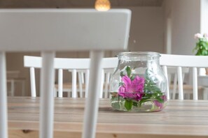 A clear glass jar with flowers on a wooden table.