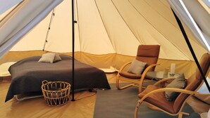 A tent with a bed, two rocking chairs, a small table, and a basket.