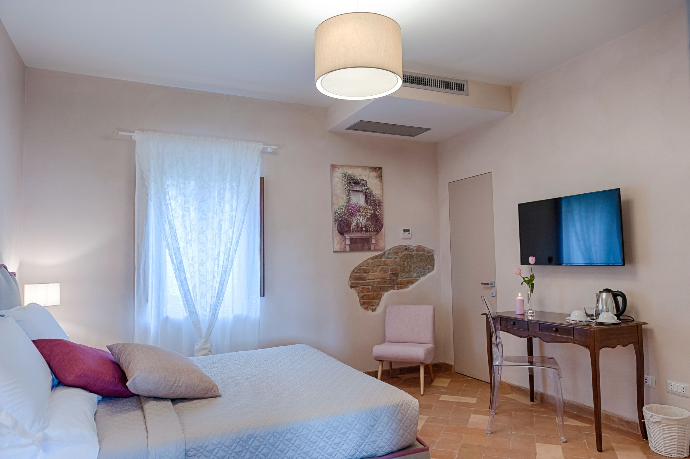 A bedroom with a bed, a desk, a chair, a TV, and a wall-mounted artwork.