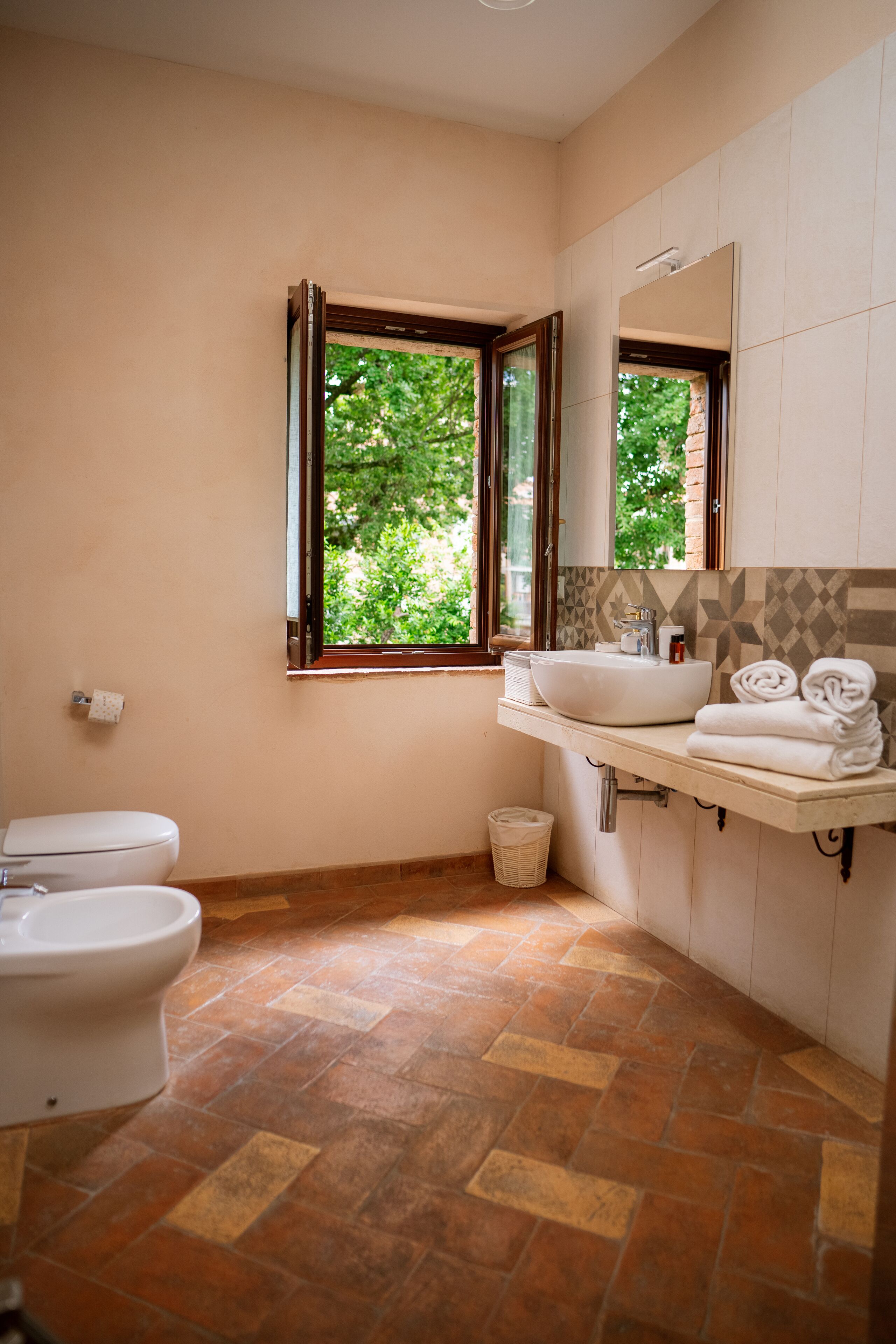 Een badkamer met toilet, wastafel en raam.
