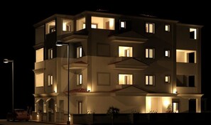 Een hotel met meerdere verdiepingen, verlichte ramen en balkons, een duidelijke ingang en een lantaarn in de buurt.