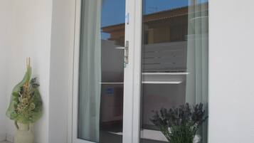 A modern building with a sliding glass door, a potted plant, and a tiled floor.