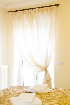 Ein Hotelzimmer mit Bett, Vorhang und Fenster.