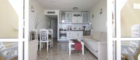 Un espacio habitable compacto con kitchenette, comedor y zona de estar.