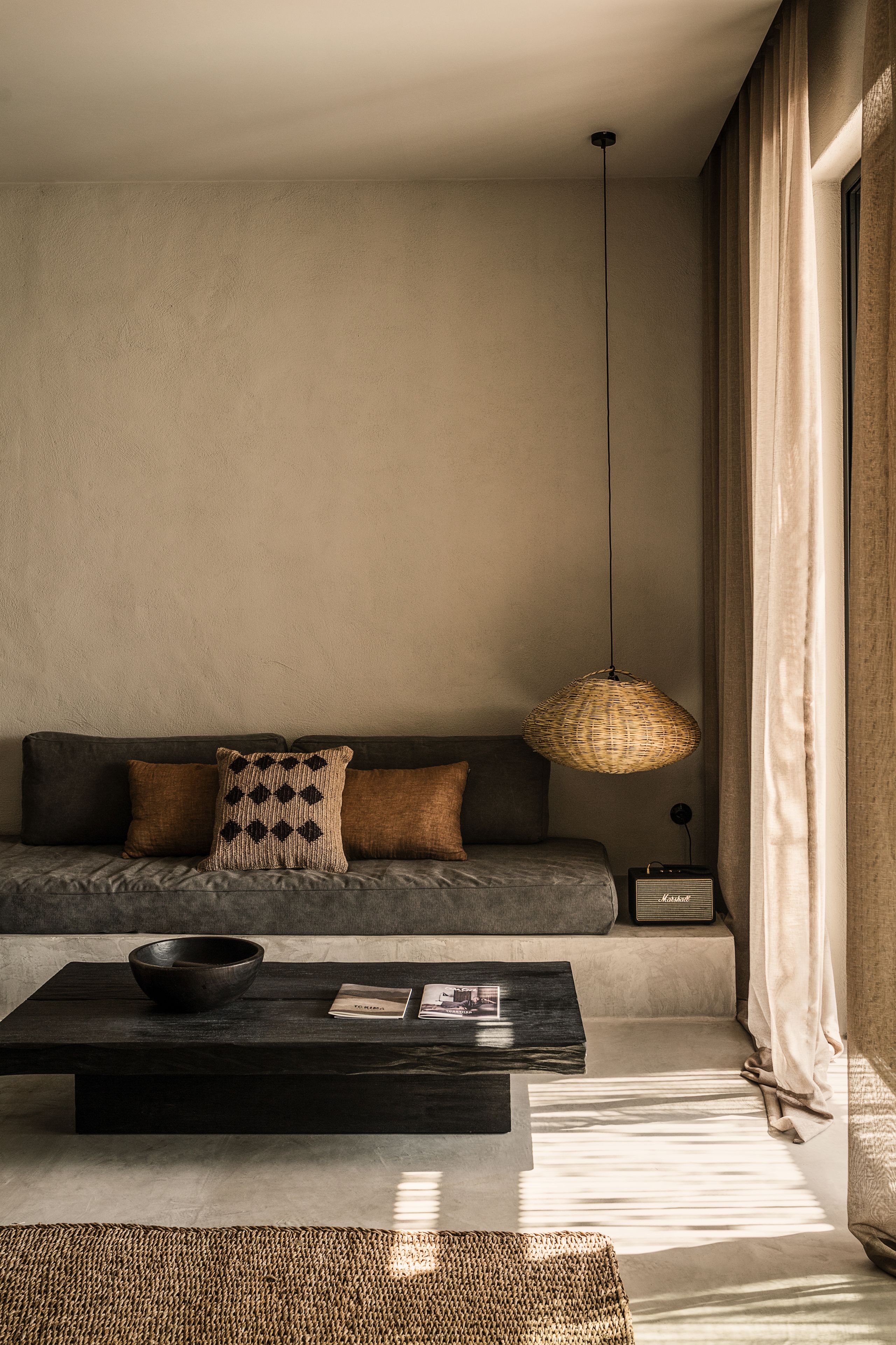 A modern living room with a sofa, a coffee table, and a hanging light fixture.