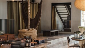 A spacious room with a large tree, a wooden table with bottles, and a staircase.