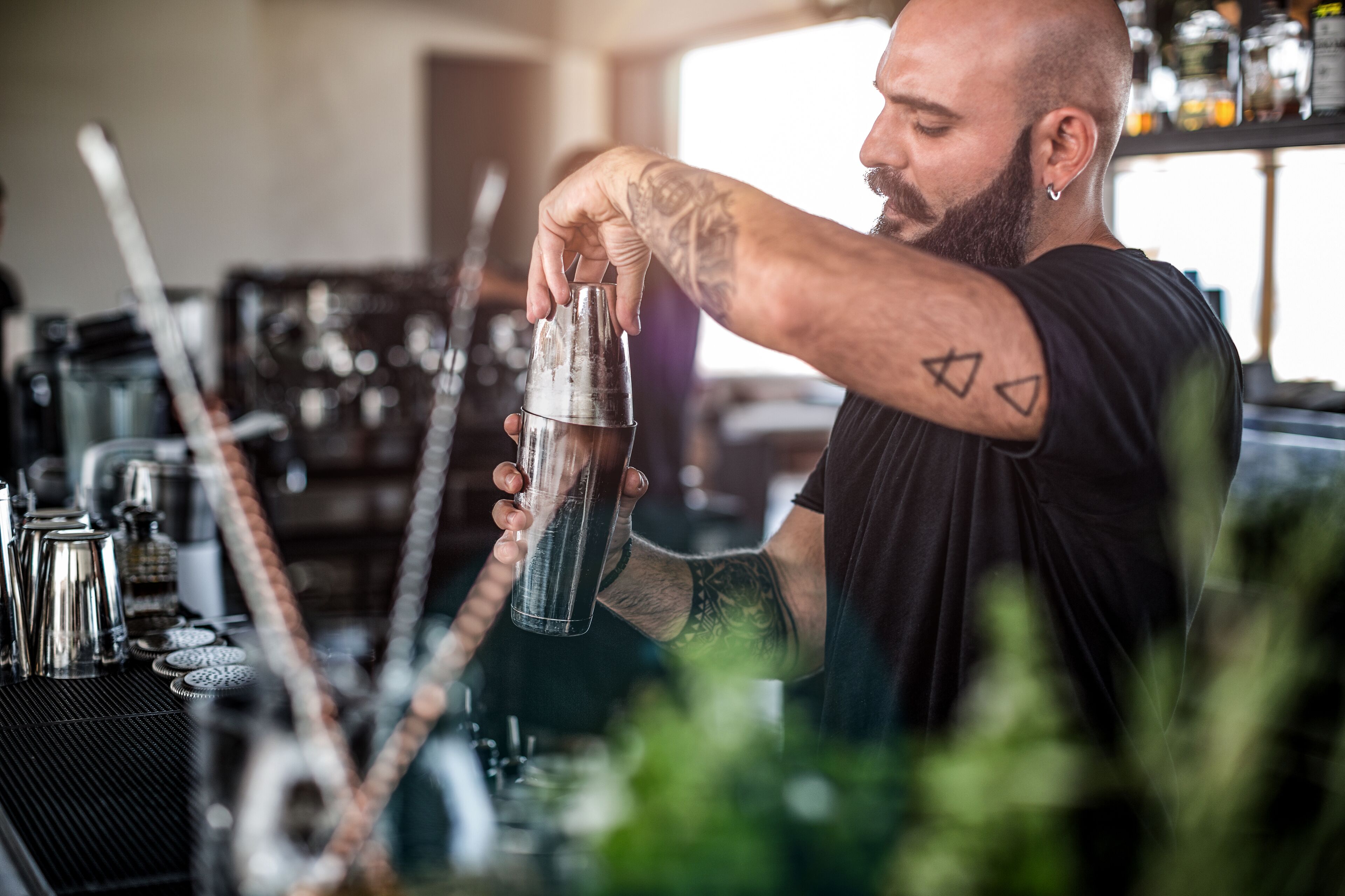 Ein Barkeeper bereitet einen Cocktail mit einem Shaker und einer Spirituosenflasche zu.
