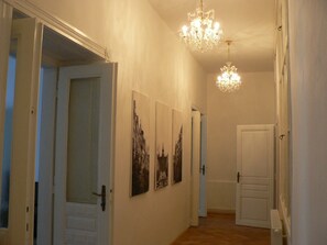 A hallway with two chandeliers, a white door, and three framed pictures on the wall. - Apartments 39 Wenceslas Square (Prague)