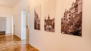 Un pasillo con piso de madera y paredes blancas, con tres fotografías en blanco y negro de edificios.