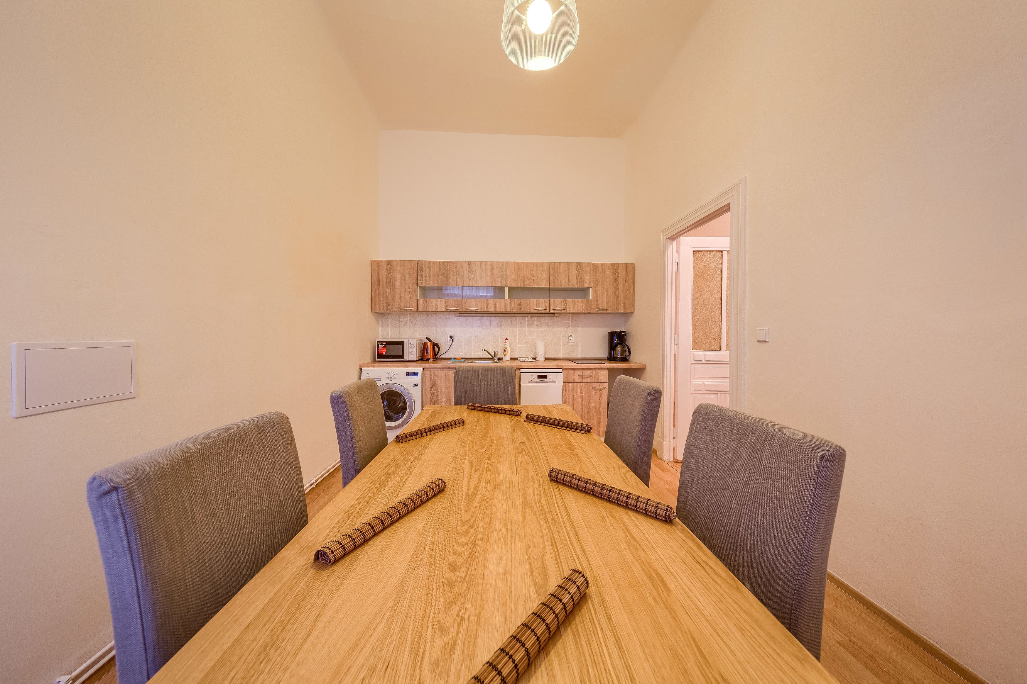 A modern kitchen with wooden cabinets, a built-in oven, and a coffee machine.