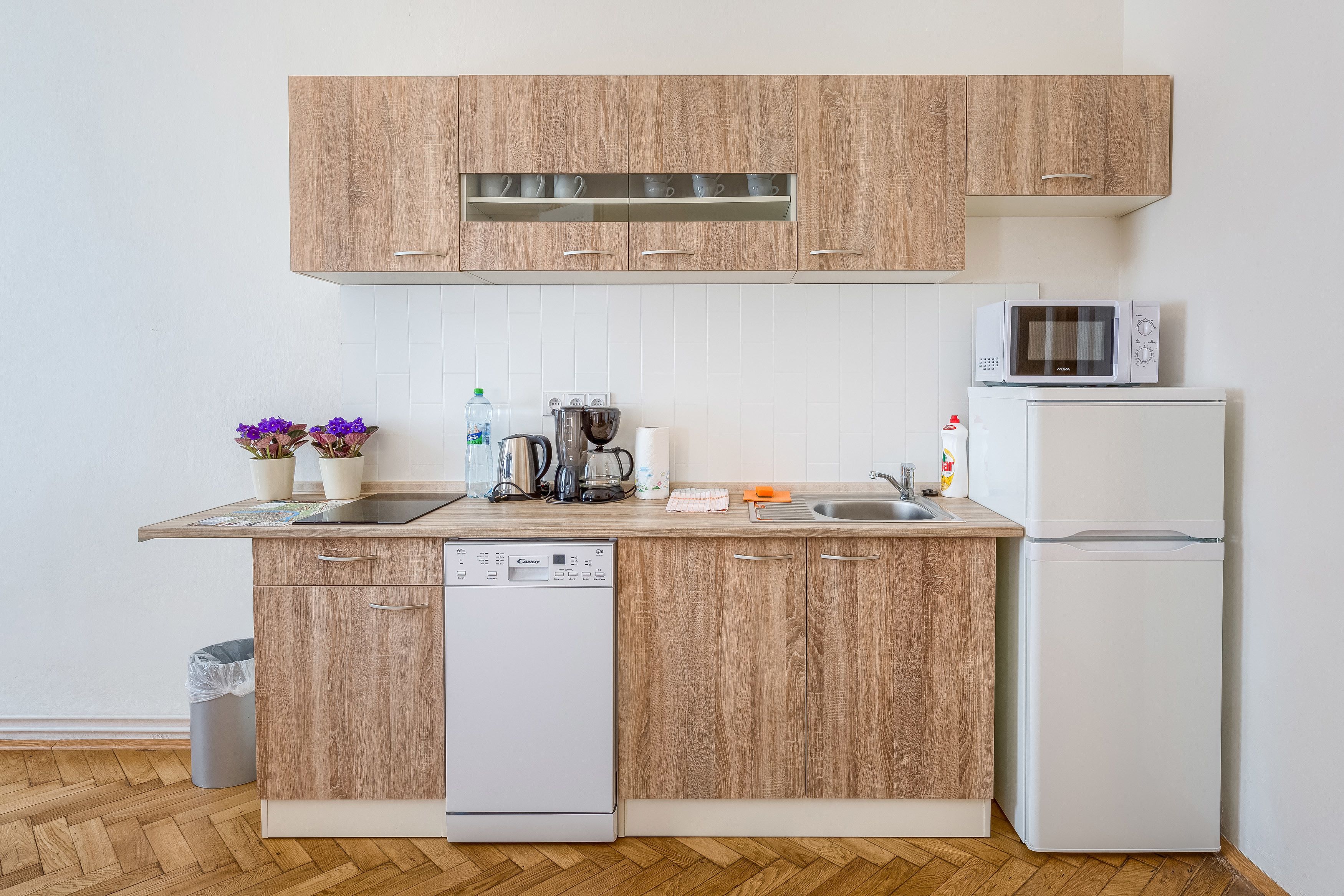 A modern kitchen with wooden cabinets, a built-in microwave, a dishwasher, and a refrigerator.