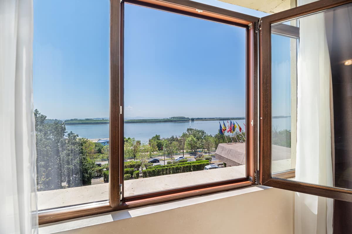 A window with a view of a lake, buildings, and flags.