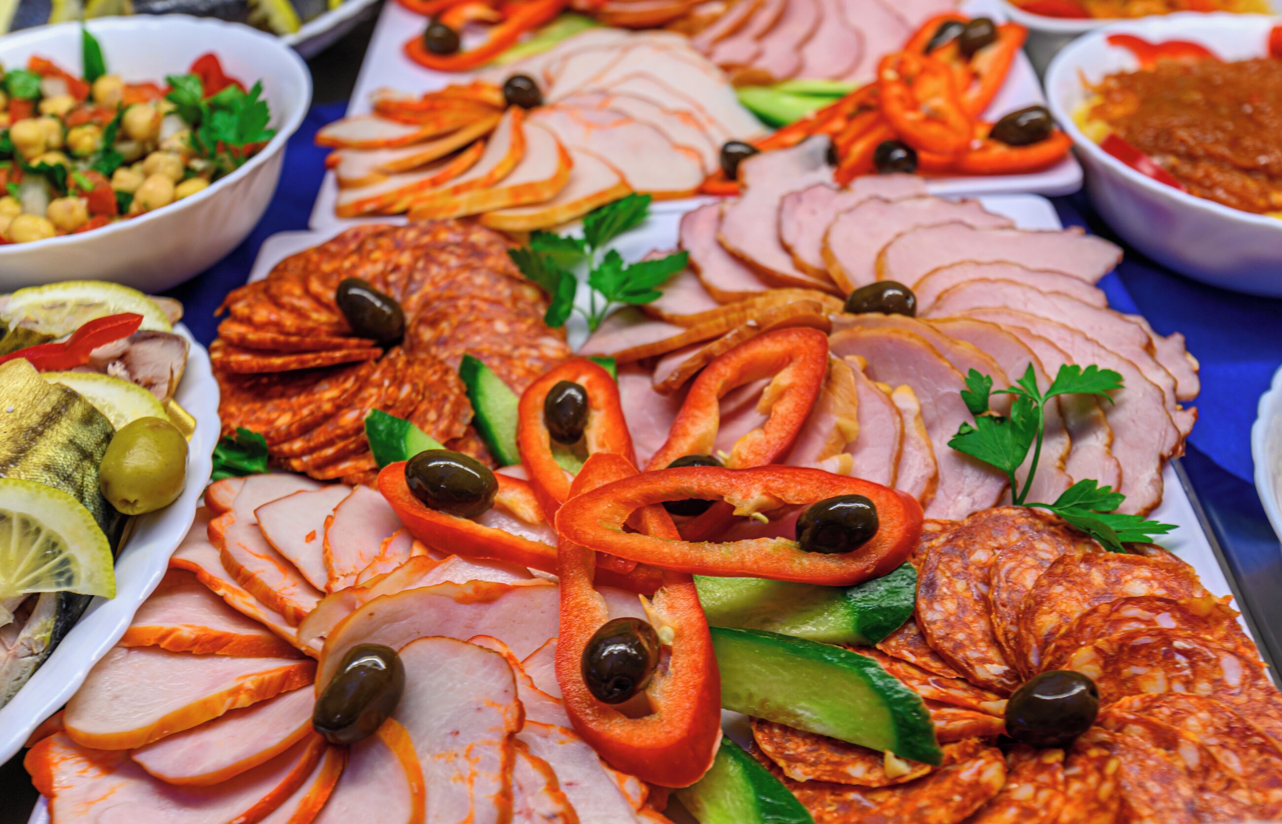 Diversos alimentos como embutidos, aceitunas y verduras dispuestos sobre una mesa.