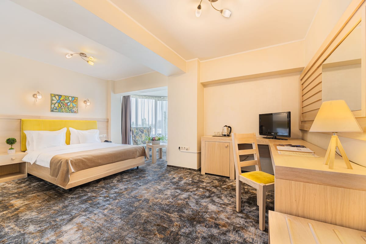 A hotel room with a bed, desk, TV, and a small cabinet.