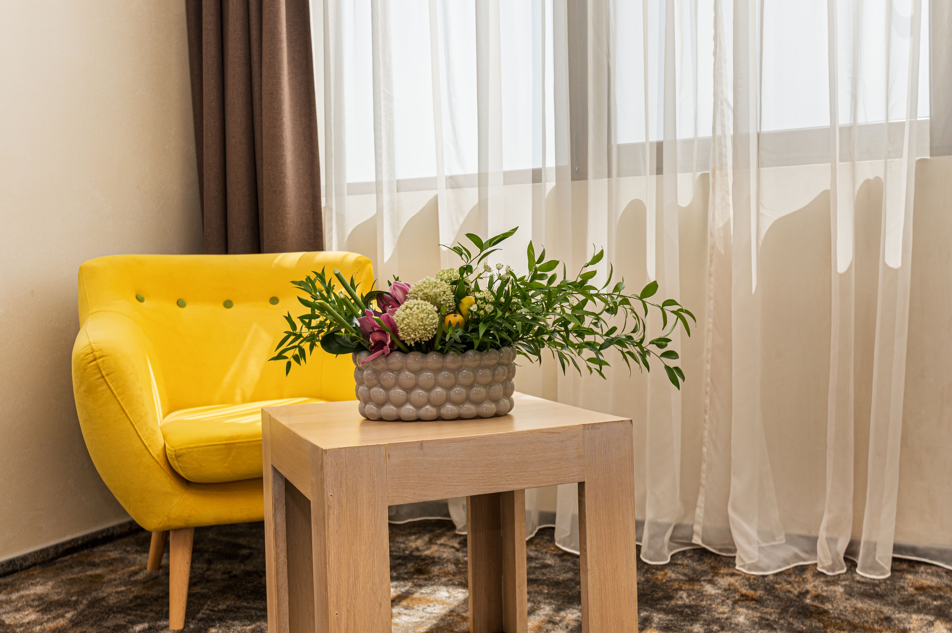 Un sillón amarillo junto a una mesa de madera con una planta en maceta.