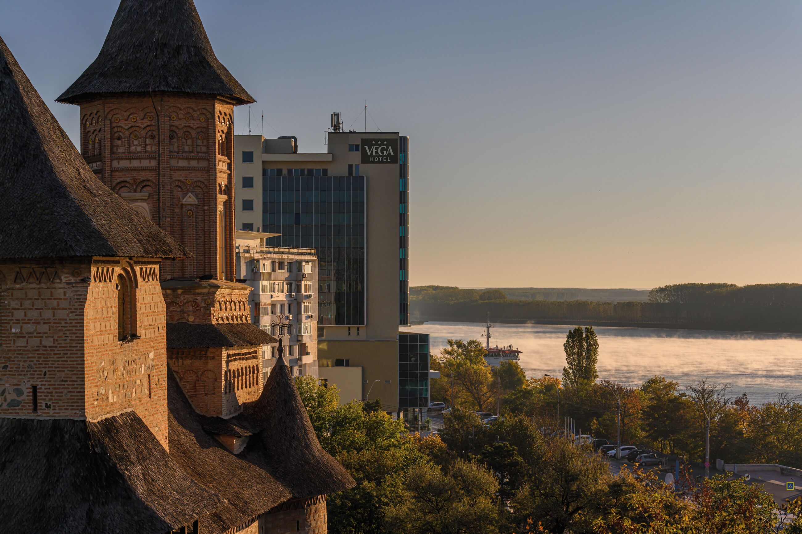 Ein historisches Gebäude mit einem Turm und ein modernes Hotel neben einem Fluss.