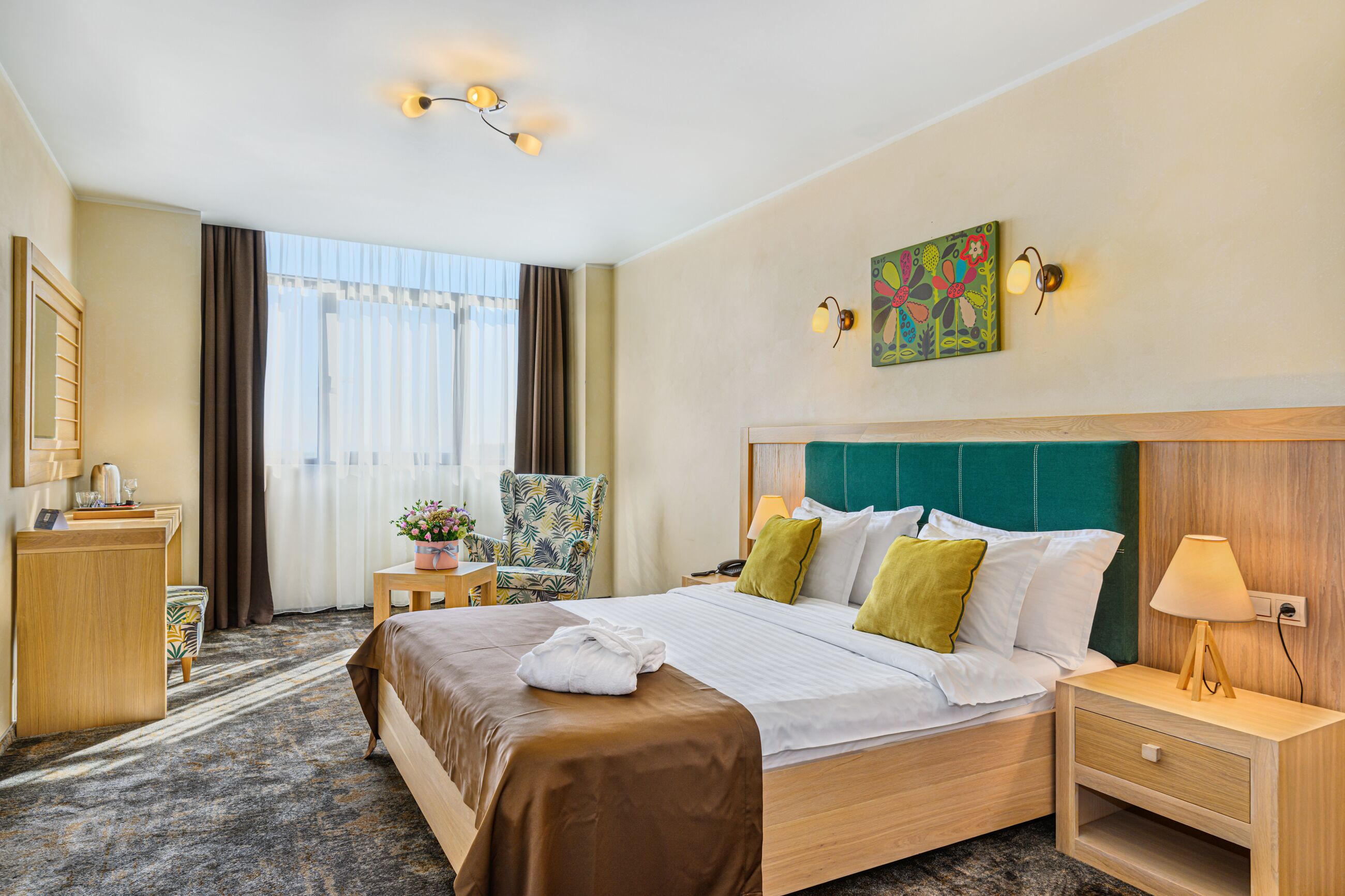Una habitación de hotel con una cama grande, un escritorio, una silla y una ventana con cortinas.
