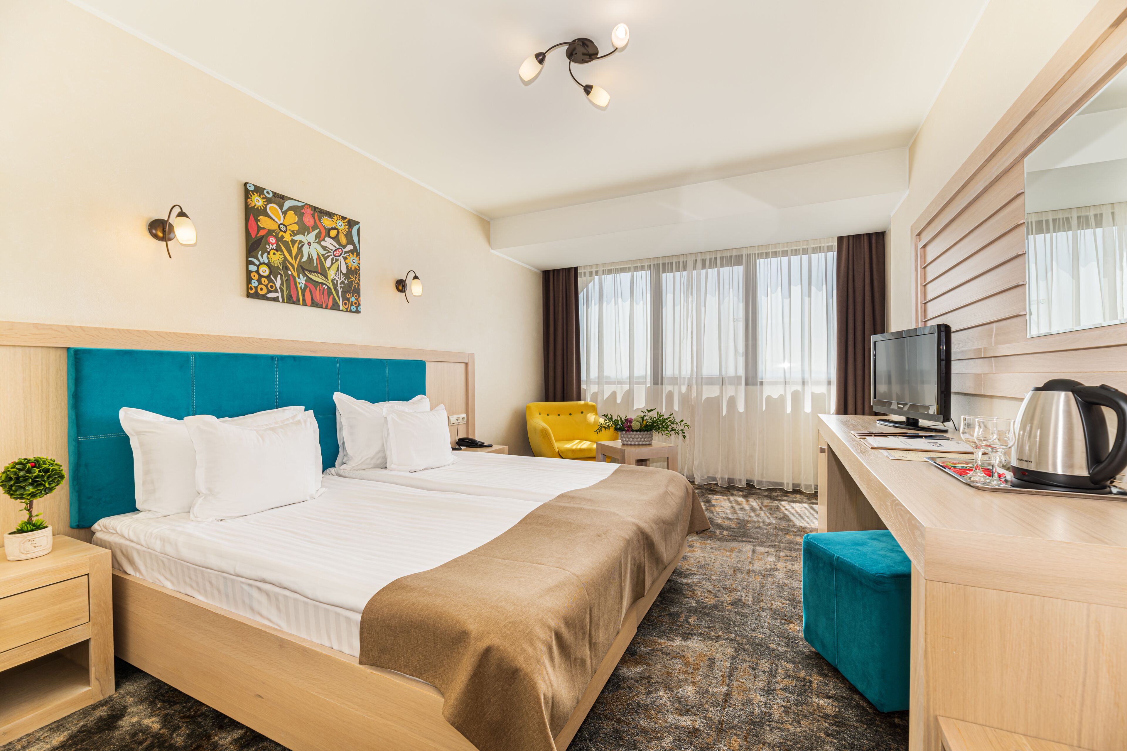 A hotel room with a large bed, a desk with a computer, a TV, and a coffee maker.