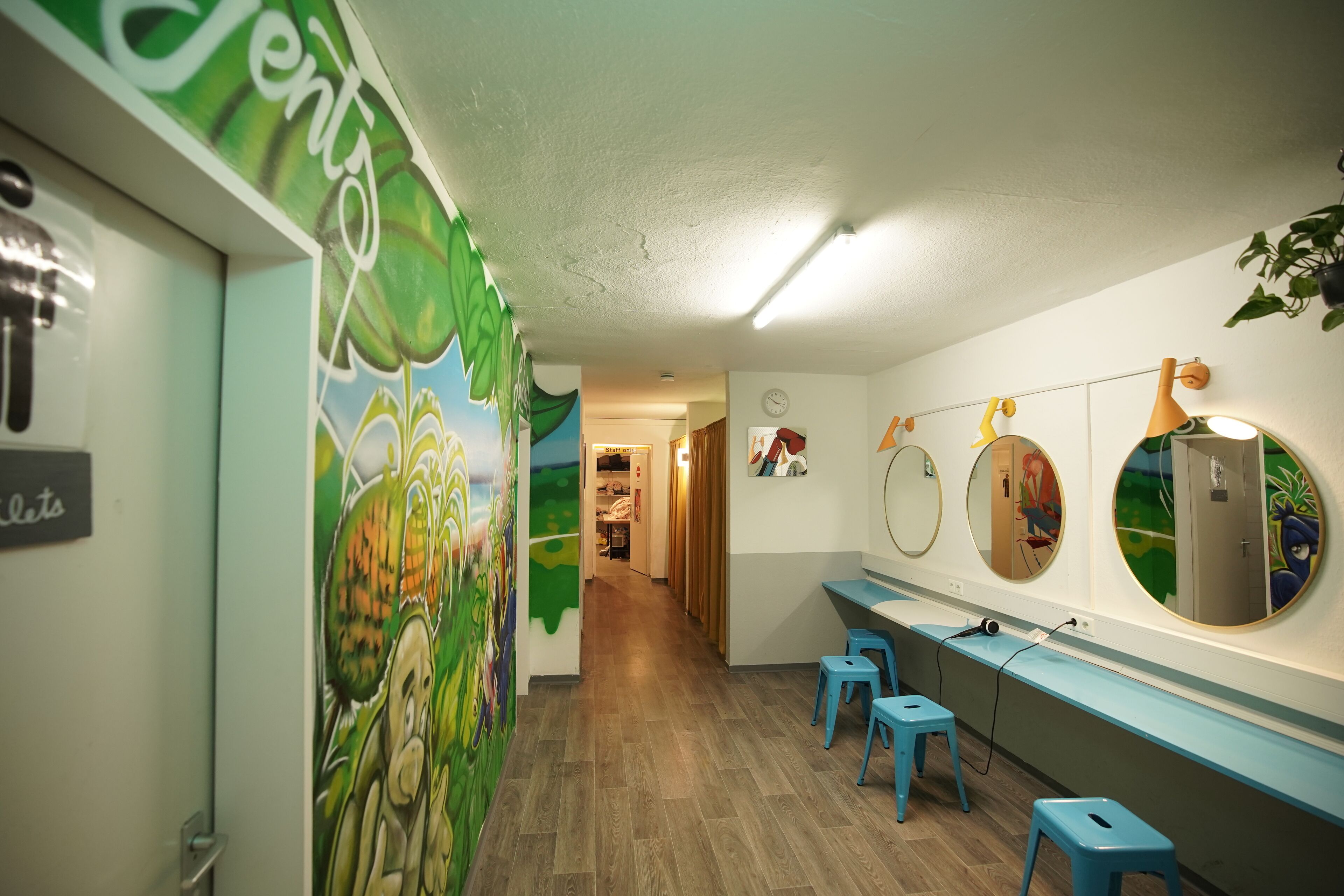 Un cuarto de juegos infantil con murales coloridos, una barra larga con taburetes y espejos en la pared.