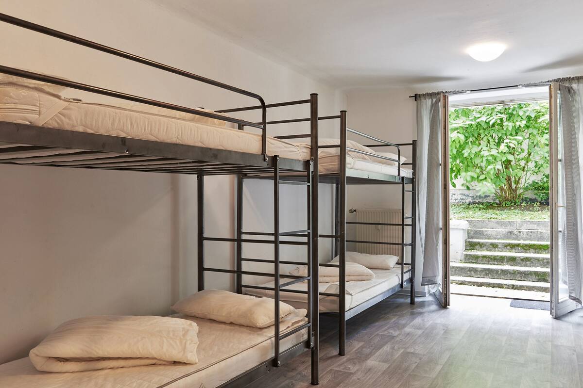 A bunk bed room with a view of a garden through a glass door.