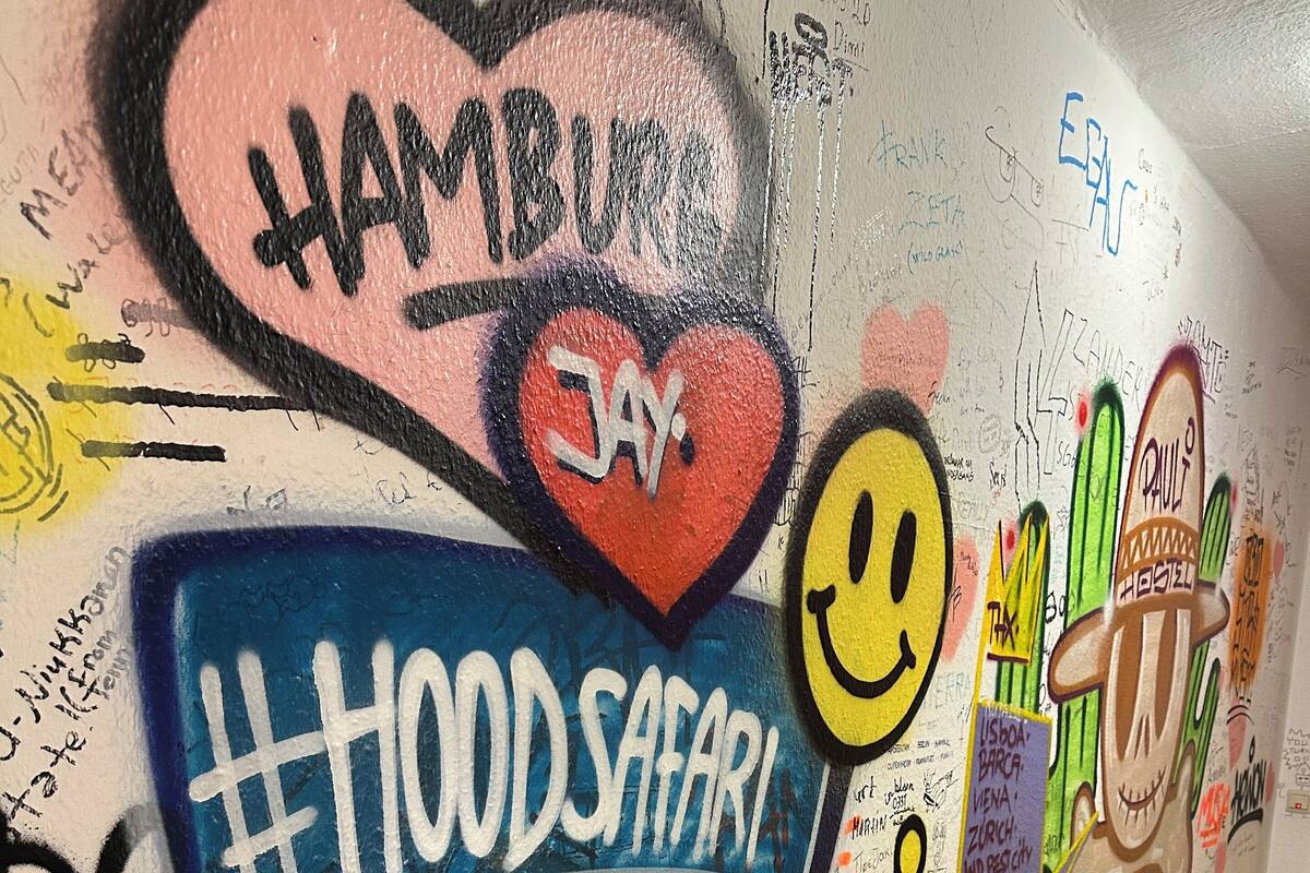 A wall covered with colorful graffiti and stickers, including a heart with "Hamburg Jay" and a smiley face.