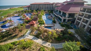 A resort with multiple swimming pools, a large building with a red roof, and a view of the ocean. - Arcadia seaside holiday hotel Beidaihe (Qinhuangdao)