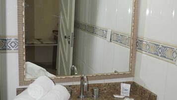 Un baño con lavamanos, espejo y toallas.