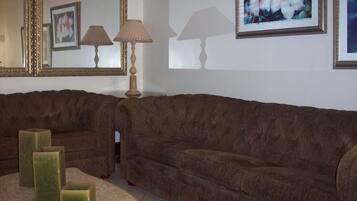 A living room with a brown sofa, a lamp, and a mirror.